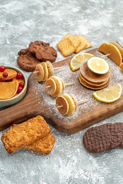 Vertical view of easy pancakes with lemons on cutting board and cookies honey on blue