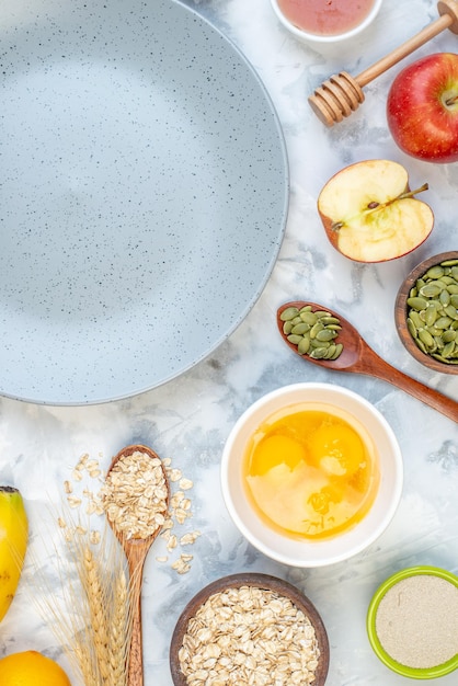 Vertical view of empty gray plate and ingredients for the healthy food set on ice background