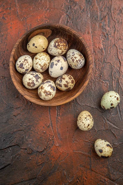 Vertical view of farm fresh egg inside and outside a wooden pot on a brown table
