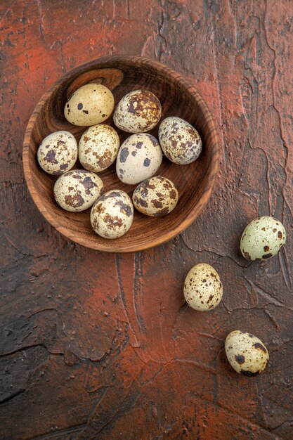 Vertical view of farm fresh egg inside and outside a wooden pot on a brown table