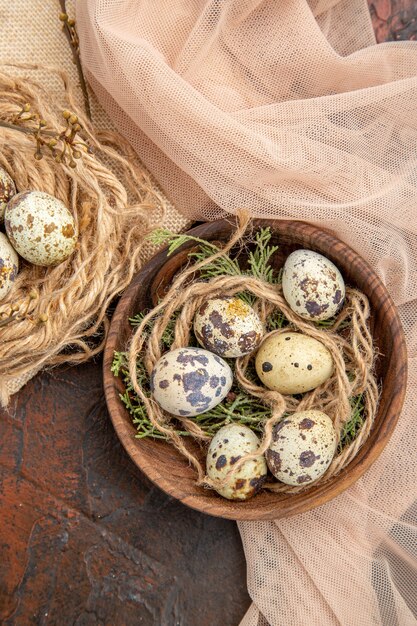 Vertical view of farm fresh eggs on a roll of rope on bag and on a wooden pot towel on a brown table