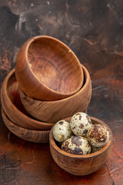 Vertical view of farm fresh eggs in wooden bowls on a brown background