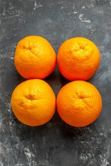 Vista verticale di quattro arance fresche organiche naturali allineate in due file su sfondo scuro