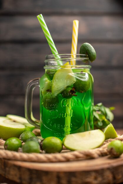 Vertical view of fresh delicious fruit juice served with apple and feijoas on a wooden cutting board on a brown table