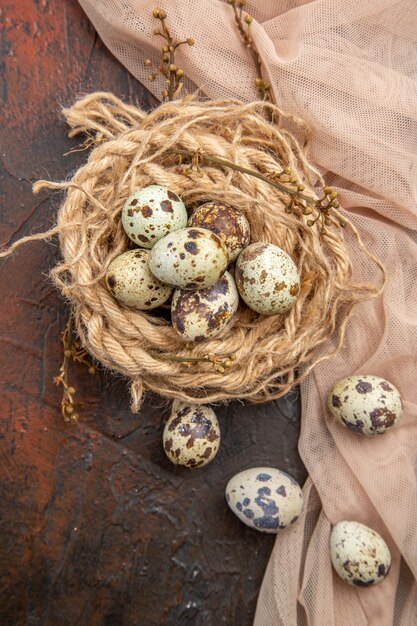 Вертикальный вид свежих яиц на мотке веревки и полотенце на коричневом столе