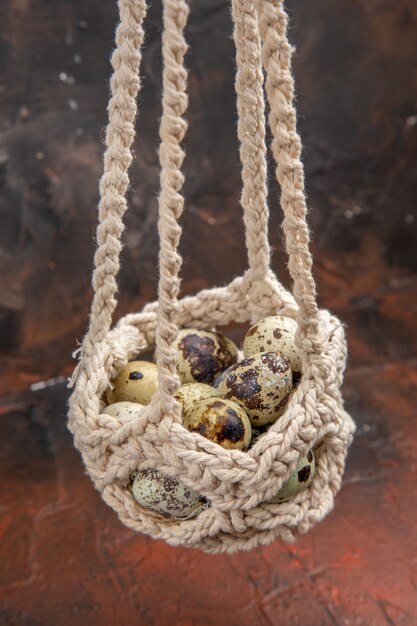 Vertical view of fresh eggs in a white hanging basket on a brown background