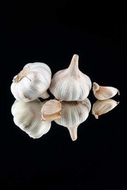Vertical view of fresh garlic cloves on black background