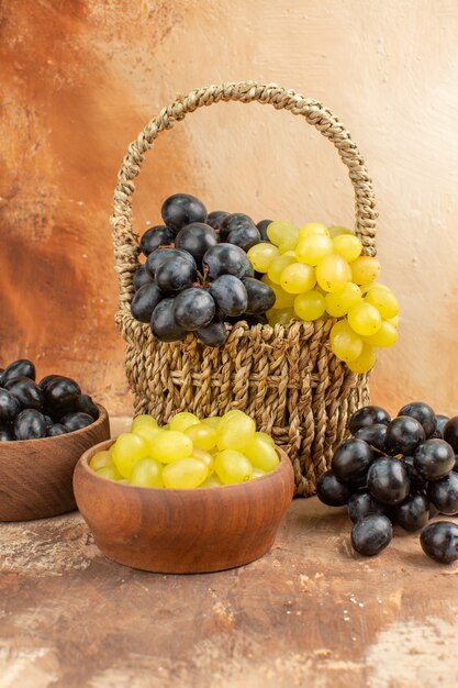 Vertical view of fresh grapes in black and yellow colors in a wooden basket small pots and