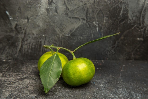 Vertical view of fresh green mandarins with leaves on gray background