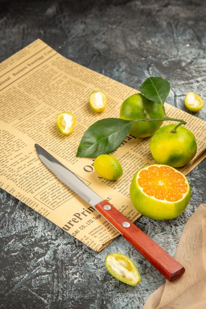 Vertical view of fresh lemons in a fallen black basket on towel knife and newspaper on gray table