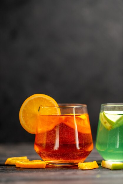 Вертикальный вид свежего натурального вкусного сока в двух стаканах с фруктовым лаймом на черном фоне