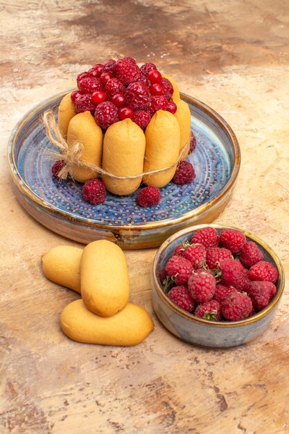 Vertical view of freshly baked soft cake with fruits and biscuits flowers on mixed color table