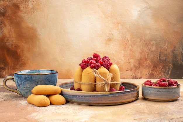 Free photo vertical view of freshly baked soft cake with fruits and tea in a blue cup on mixed color table