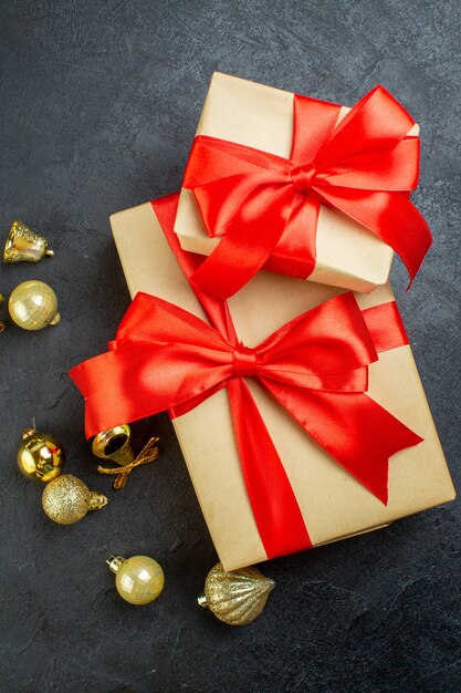 Vertical view of gift box with red ribbon and decoration accessories on dark background