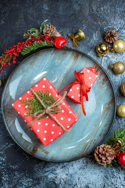 Vertical view of gift boxes on a blue plate decorative accessories conifer cone on dark background