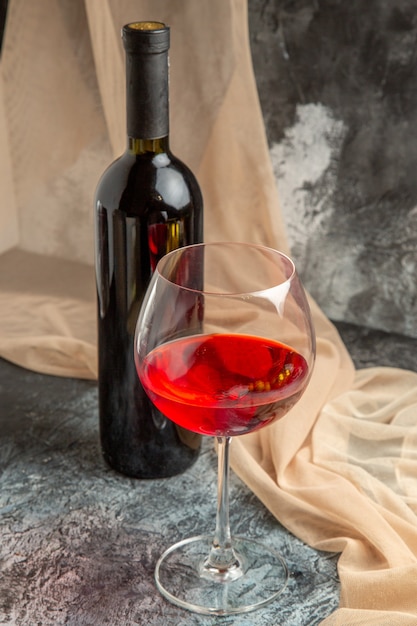 Вертикальный вид бокала и бутылки с восхитительным сухим красным вином и полотенцем на ледяном фоне