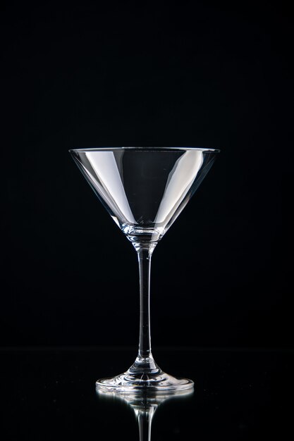 Вертикальный вид стеклянного бокала для вина, стоящего на черном фоне