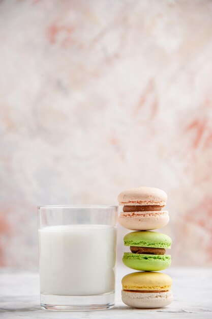 Vertical view of a glass of milk and colorful delicious macarons on pastel colors background with free space