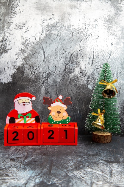 Vertical view of golden ring bell hanging on pine tree for Christmas holiday and inscription with new year toys on gray background