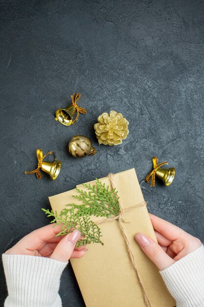 Vertical view of hand holding gift box and decoration accessories on dark background