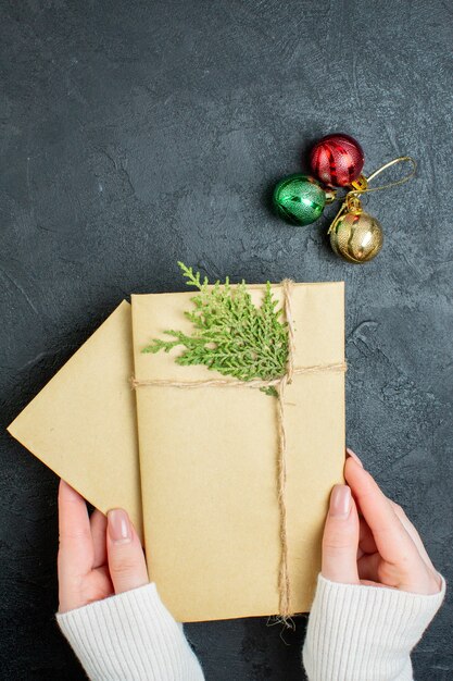 Vertical view of hand holding gift boxes and decoration accessories on dark background