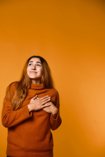 Vertical view of happily mused redhead attractive caucasian woman dressed in pullover