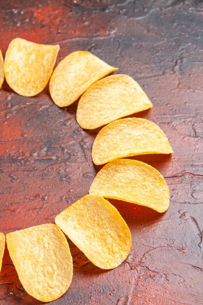 Vertical view of homemade delicious crispy chips on dark background with free place