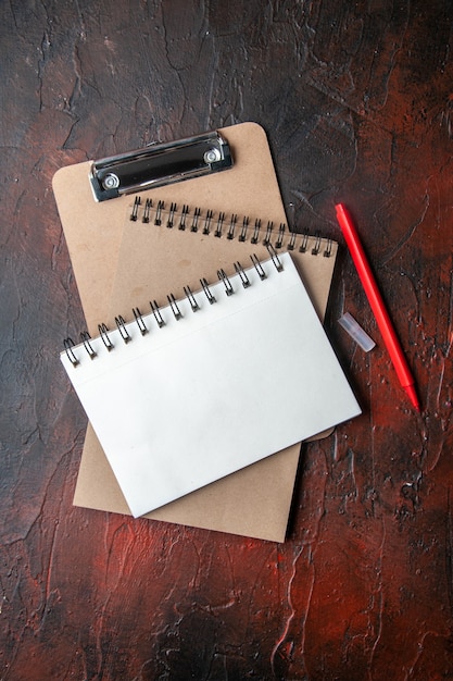 Vertical view of kraft spiral notebooks with pen on dark background