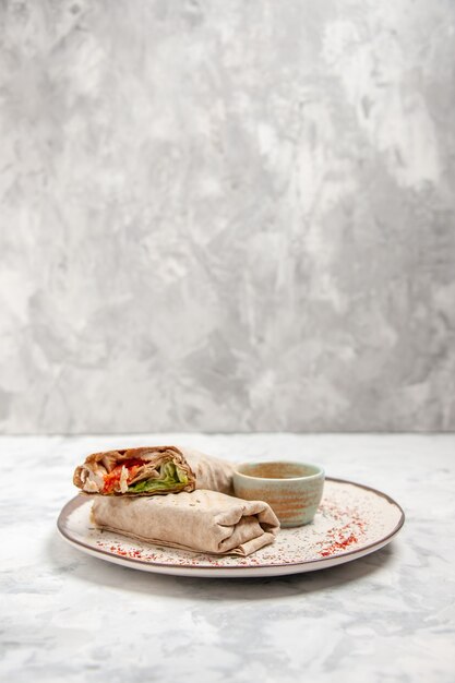 Vertical view of lavash wrap and yogurt in a small bowl on a plate on stained white surface