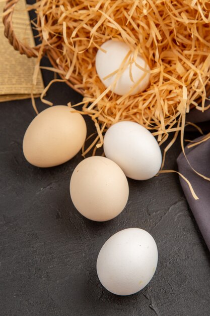 Vertical view of many organic eggs inside and outside a basket on an old newspaper on black towel rope on dark background