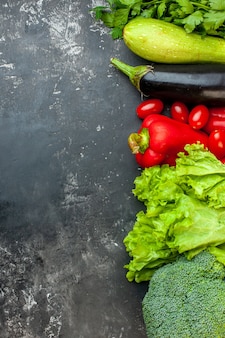 Вертикальный вид приготовления обеда со свежими овощами и зеленью слева на темном фоне