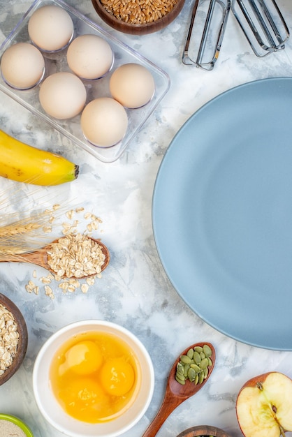 Вертикальный вид пустой тарелки и ингредиентов для здоровой пищи на бело-голубом фоне