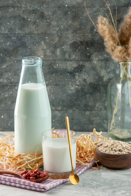 Вертикальный вид открытой чашки стеклянной бутылки, наполненной молоком и фасолью в ложке на фиолетовом полосатом полотенце