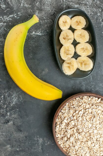 Vertical view of organic nutrition source fresh banana oat bran in a brown pot on dark background