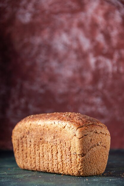 Vertical view of packed black bread on maroon distressed background with free space