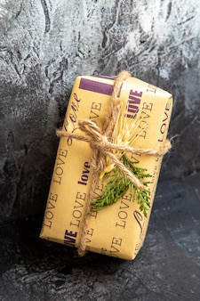 Vertical view of packed gift standing on wall on dark background