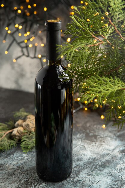 Vertical view of red wine bottle and fir branche on gray background