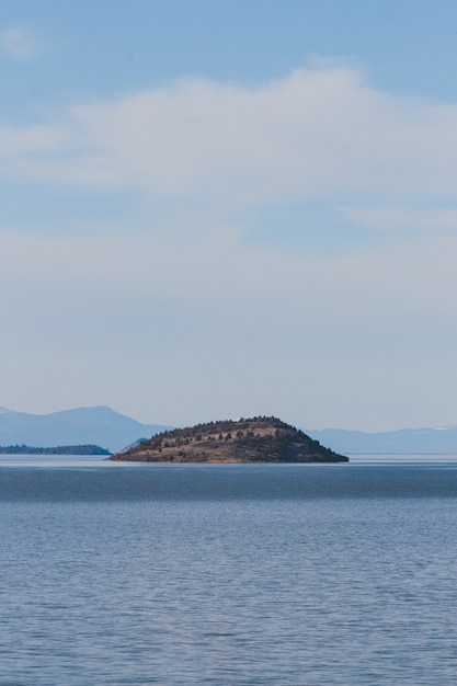Вертикальный вид на море, окружающее остров, под облачным небом в дневное время