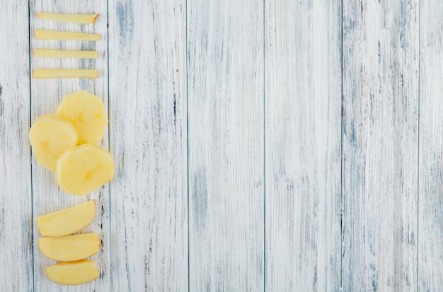 Vertical view of sliced potato on left side and wooden background with copy space