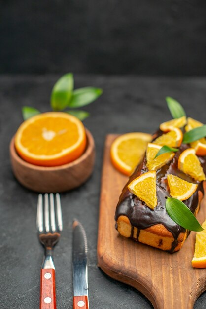 ボード上の柔らかいケーキと暗い背景の葉でレモンをカットの垂直方向のビュー