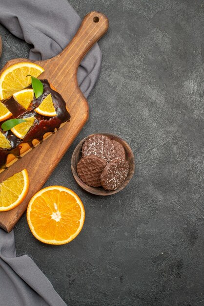 Vertical view of soft tasty cakes cut lemons with biscuits on wooden cutting board