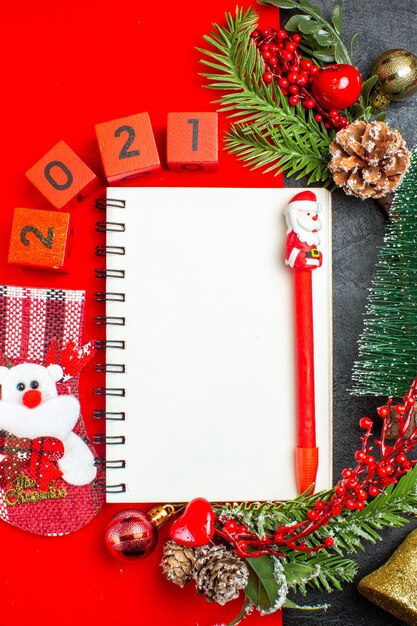 나선형 노트북 장식 액세서리 전나무 가지 크리스마스 양말 번호 빨간색 냅킨 및 어두운 배경에 크리스마스 트리의 세로보기
