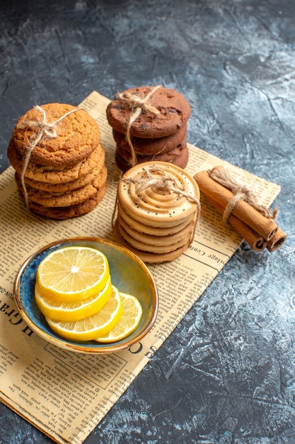 Vertical view of stacked delicious cookies cinnamon lemon on an old newspaper on dark background