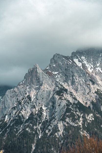 Vertical view of a tall mountain under the cloudy sky