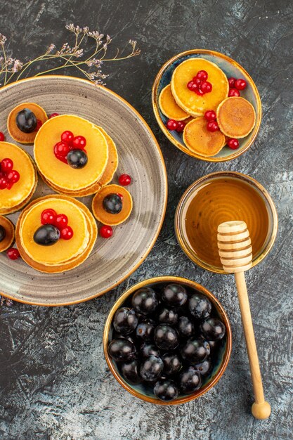 Vertical view of tasty breakfast with classic pancakes served with honey and black cherry