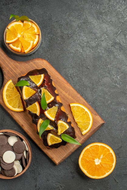 Vista verticale di gustose torte tagliate i limoni con biscotti sul tagliere sul tavolo scuro