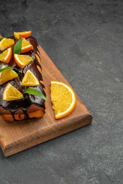 Vertical view of tasty cakes decorated with lemon and chocolate on cutting board on black table