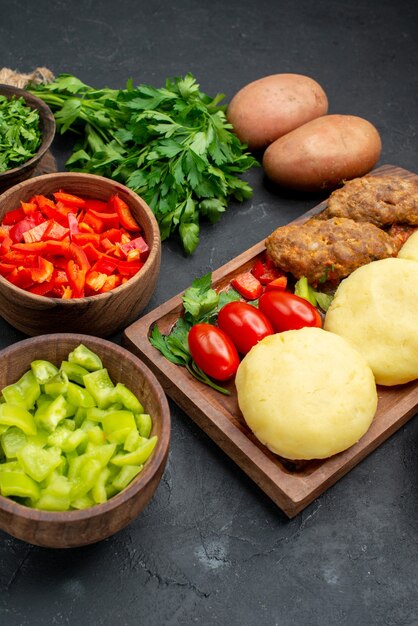 Vertical view of tasty cutlets with vegetables and a bunch of green on dark table