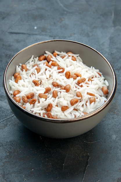 Vertical view of tasty rice meal with beans in a brown small pot on the left side on blue background