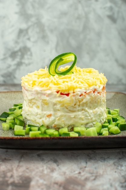 Foto gratuita vista verticale di una gustosa insalata servita con cetriolo tritato su sfondo di colore misto